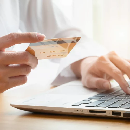 hands-woman-buys-online-holding-credit-card-with-laptop-table