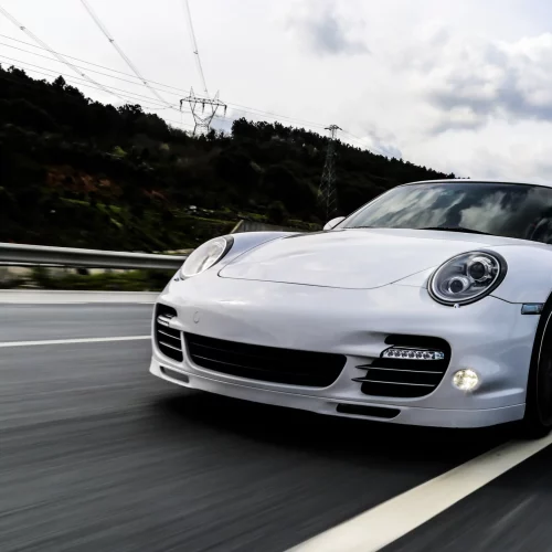 white-coupe-driving-road